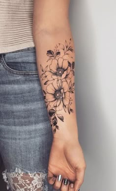 a woman's arm with black and white flowers tattooed on the left side of her arm