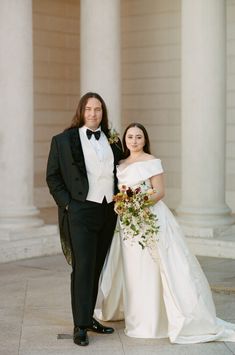 a man and woman in formal wear standing next to each other on the steps of a building