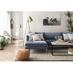 a living room with blue couches and pillows on the floor in front of a white wall