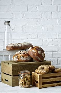 breads and other baked goods are on display in front of a white brick wall