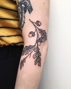 a woman's arm with a branch and leaves tattoo on the left side of her arm