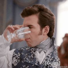 a man drinking water from a glass while wearing a vest and bow - necked shirt