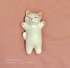 a white cat laying on top of a pink surface with its eyes closed and it's arms stretched out