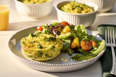 an omelet on a plate with salad and orange juice in the back ground