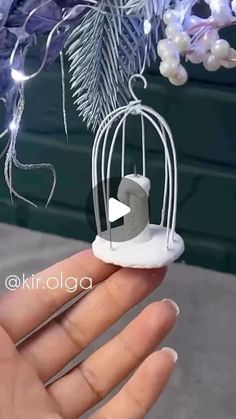 a hand holding a miniature bird in a cage