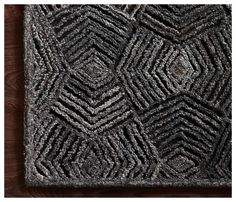 a black and white rug with an intricate design on the front, along with a wooden floor