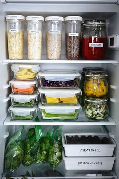 an open refrigerator filled with lots of food and containers full of different types of vegetables