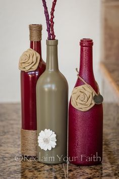 three wine bottles decorated with flowers and twine