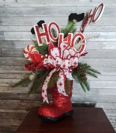 a red boot filled with holiday decorations on top of a wooden table