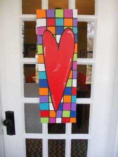 a door decorated with a heart on the side and colorful squares in the front window