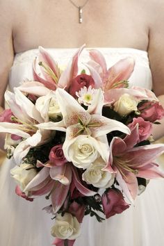 a bride holding a bouquet of pink and white flowers