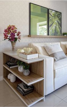 a living room with a white couch and two vases filled with flowers on the table