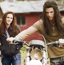 two people standing next to each other near a motorbike with long hair on it