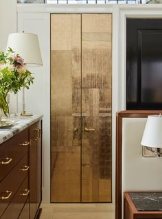 a large wooden door sitting next to a table with a lamp on top of it