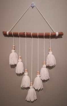 a group of white tasselled beads hanging from a wooden hanger on a wall