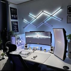 a computer desk topped with a monitor and keyboard next to a wall mounted speaker system