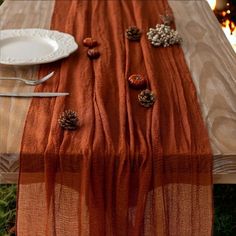 an orange table runner with pine cones on it