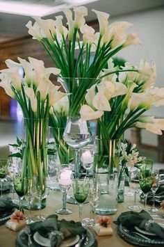 there are many flowers in the vases on this dining table set with place settings