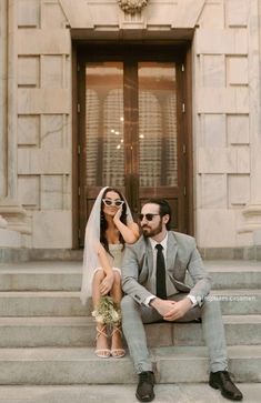 a bride and groom sitting on the steps of a building