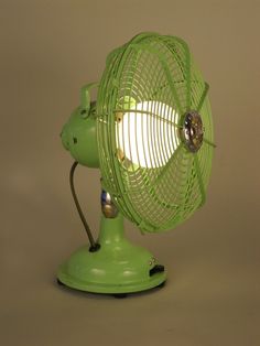 a green desk fan sitting on top of a table