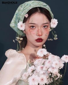 a woman with flowers in her hair and wearing a green hat, holding a bouquet of white flowers