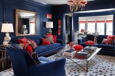 a living room with blue couches and red pillows on the walls, chandelier