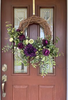 a wreath on the front door with purple flowers