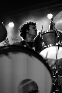 a man with curly hair playing drums on stage