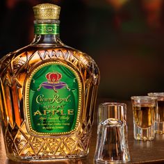 a bottle of crown royal regal apple liqueur next to two shot glasses