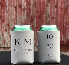 two can coolers sitting next to each other on top of a black table in front of a wooden fence