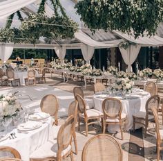 tables and chairs are set up for an outdoor wedding reception with white linen draping