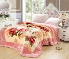 a bedroom with a bed covered in a pink flowered bedspread and pillows