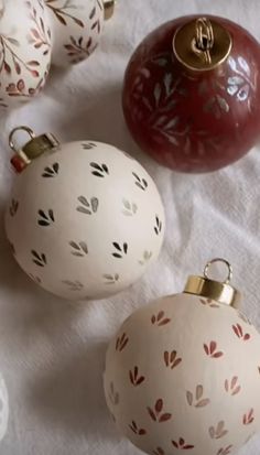 three christmas ornaments sitting on top of a white cloth covered table next to each other