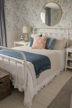 a white bed sitting in a bedroom next to a window with blue and pink pillows