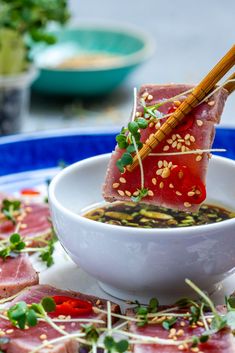 a bowl of soup with chopsticks sticking out of the meat and vegetables in it