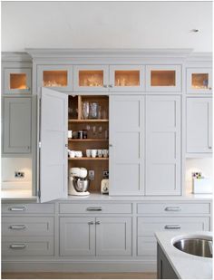 a white kitchen with lots of cabinets and counter top space in front of the sink