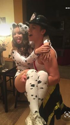 a man and woman dressed up as dalmatian dogs sitting on top of each other