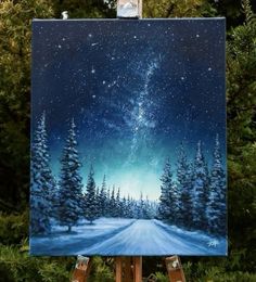 an easel with a painting on it that has snow and trees in the background