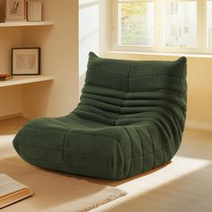 a green bean bag chair sitting on top of a wooden floor next to a window