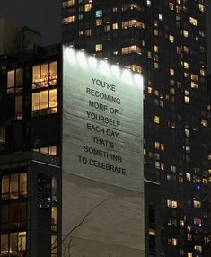 a tall building with a lit up sign on it's side that says you're becoming more of yourself each day that's something to celebrate