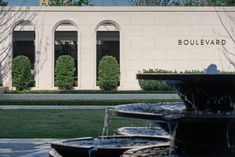 a fountain in front of a building with two windows and bushes behind it that reads boulevardard