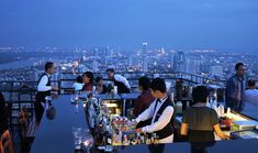 a group of people sitting at a bar overlooking the city