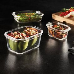 three plastic containers with food in them sitting on a table next to a cutting board