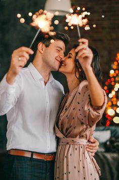 a man and woman kissing while holding sparklers