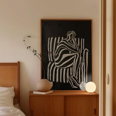 a bed room with a neatly made bed and a painting on the wall above it