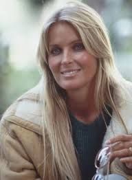 a woman with long blonde hair is holding a wine glass and smiling at the camera