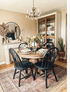 the dining room table is set for four with black chairs and an antique rug on the floor