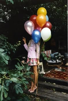 a woman is holding many balloons in her hands