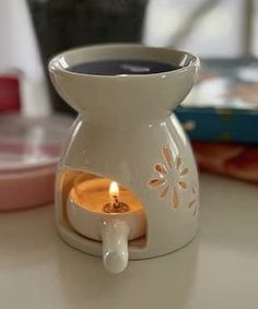 a white vase with a lit candle in it