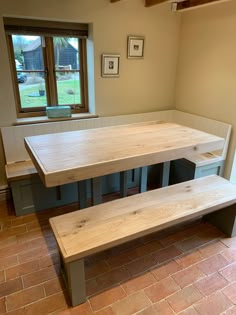 a table and benches in a room with brick flooring on the ground, next to a window